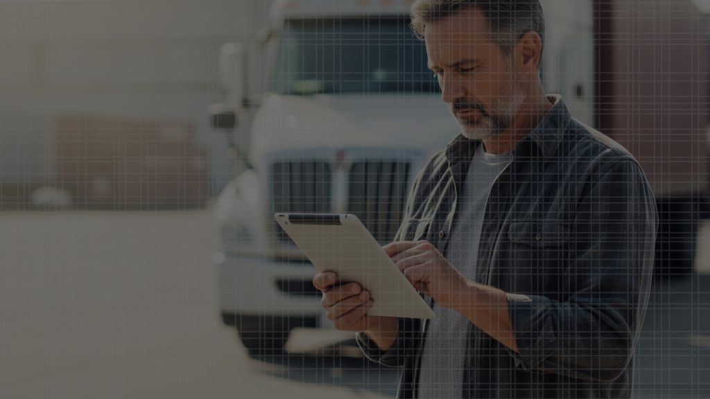 Independent truck driver in casual workwear reviewing dispatch details on a tablet