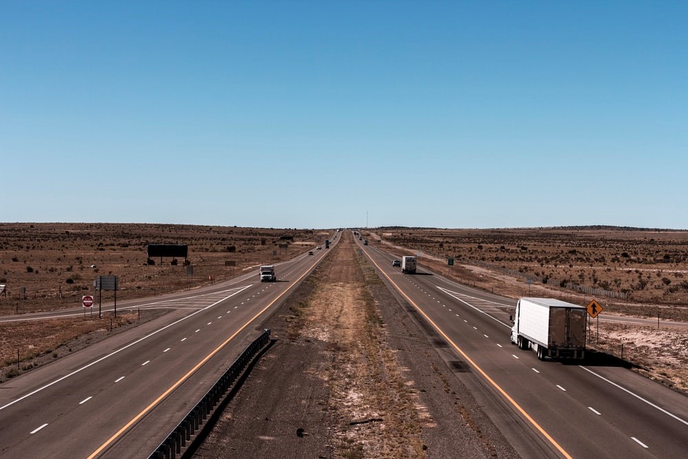 A White Truck Driving Along a Sparsely Populated Desert Road